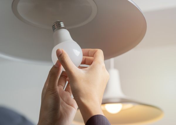 Cropped image of woman hands changing light bulb in hanging lamp at home. Moving, electricity and repair concept